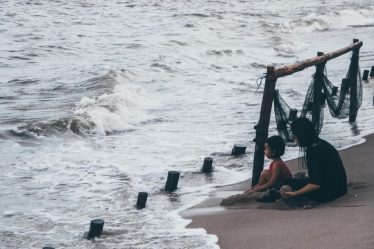 A father and son look at the stormy ocean.