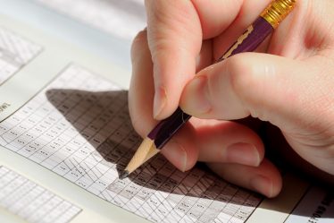 A person holding a pencil and writing on a piece of paper