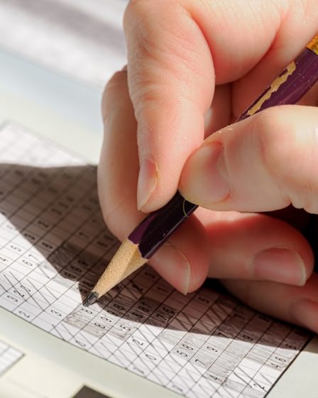 A person holding a pencil and writing on a piece of paper