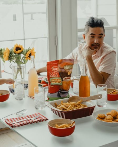 woman in white crew neck t-shirt sitting on chair in front of table with foods