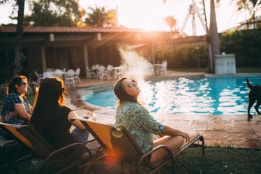 woman in white and black floral shirt sitting on chair near swimming pool during daytime
