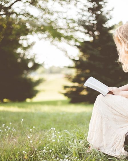 woman sitting while reading book