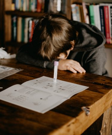 boy in gray hoodie reading book on brown wooden table