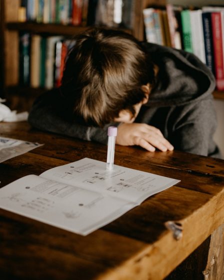 boy in gray hoodie reading book on brown wooden table