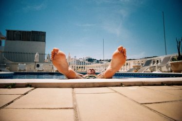 person lying on white concrete bench during daytime