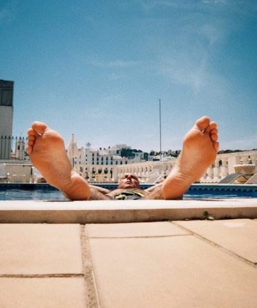person lying on white concrete bench during daytime