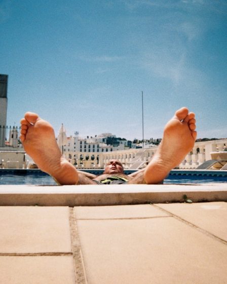 person lying on white concrete bench during daytime