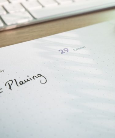 a notepad with a planner and a keyboard in the background