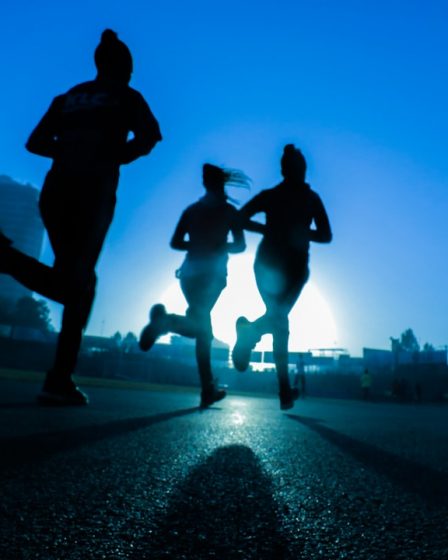 silhouette of three women running on grey concrete road