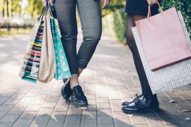 Two women with shopping bags on a sidewalk