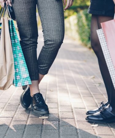 Two women with shopping bags on a sidewalk