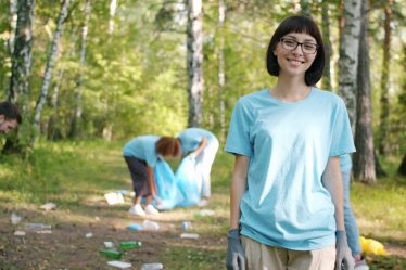 Woman smiling while people clean forest trash