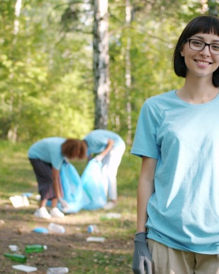 Woman smiling while people clean forest trash