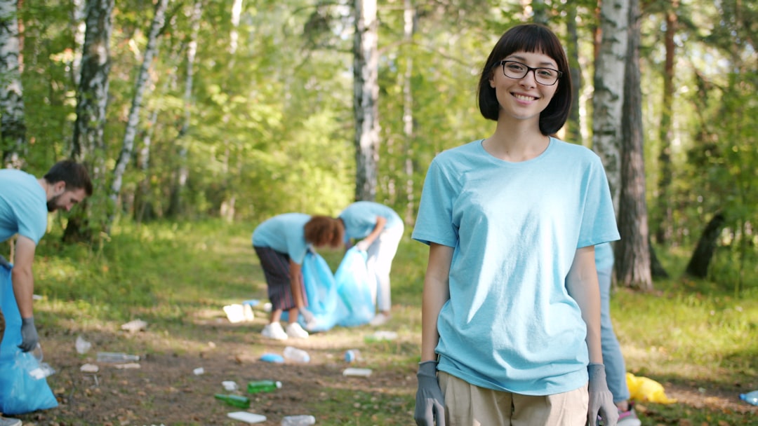 Woman smiling while people clean forest trash