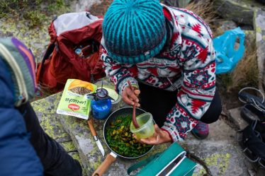 Person cooking food outdoors with portable stove