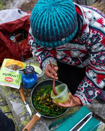 Person cooking food outdoors with portable stove