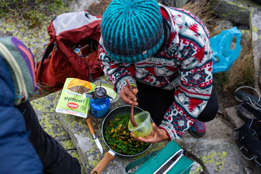 Person cooking food outdoors with portable stove