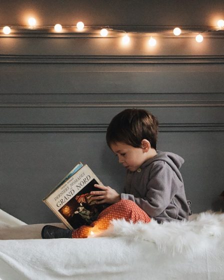 boy reading book on bed