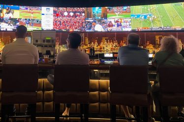 a group of people sitting at a bar watching tv