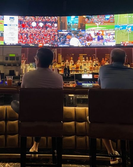 a group of people sitting at a bar watching tv