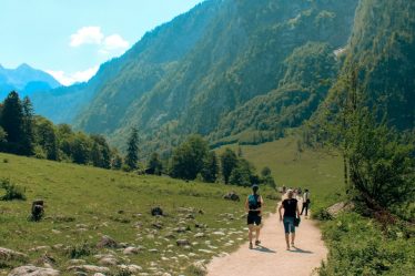 People walking on a path through green mountains and trees