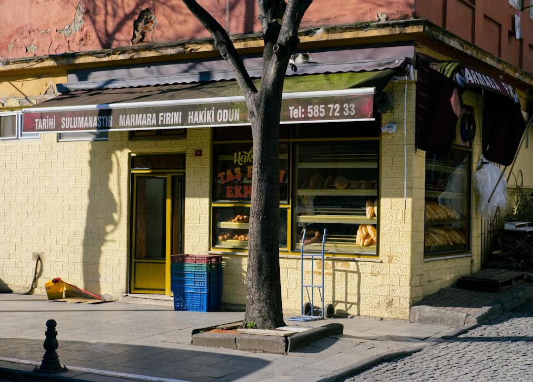 A yellow building sitting next to a tree on a street