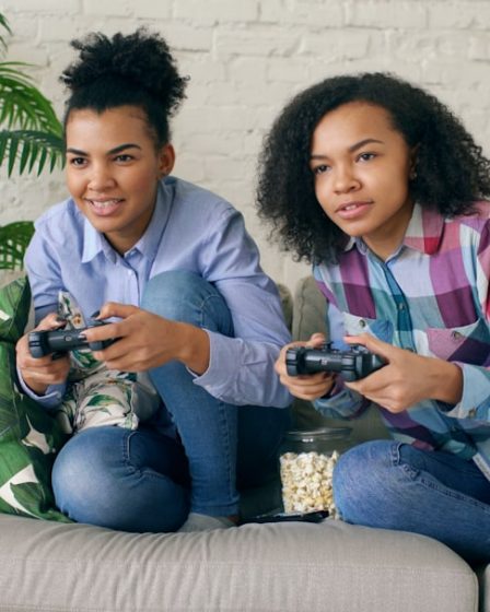 Two young women playing video games on a couch