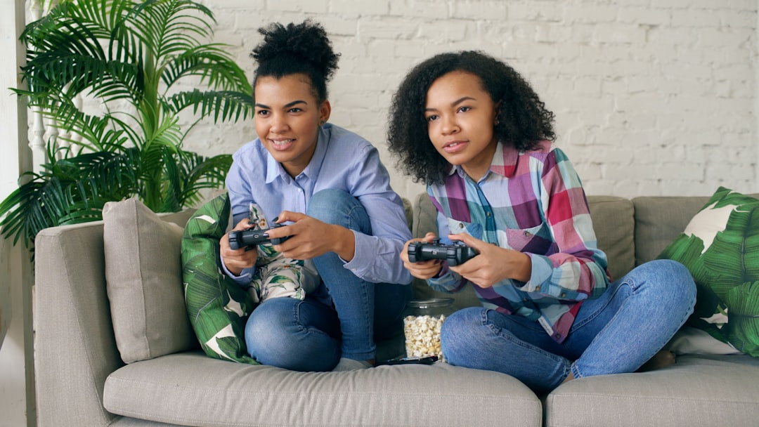 Two young women playing video games on a couch