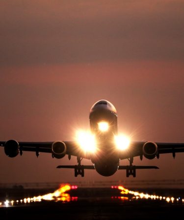 A passenger airplane taking off from a runway at night with bright landing lights