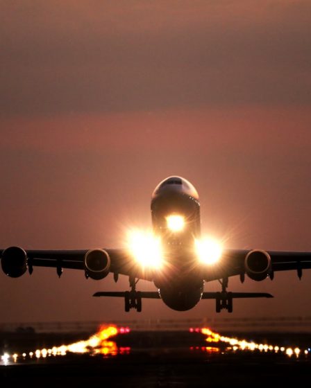 A passenger airplane taking off from a runway at night with bright landing lights