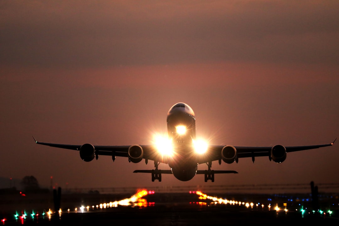 A passenger airplane taking off from a runway at night with bright landing lights